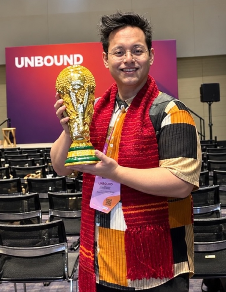 Matthew holding the winner&rsquo;s trophy in front of a HubSpot Unbound conference backdrop.
